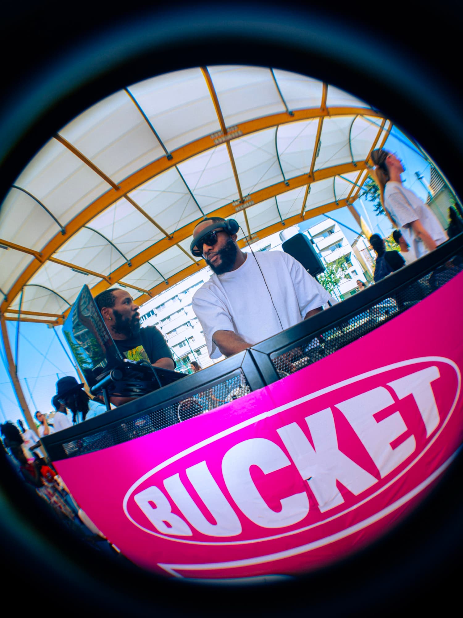 Le DJ derrière sa table de mixage BUCKET, photographié à l’objectif fisheye sous la halle