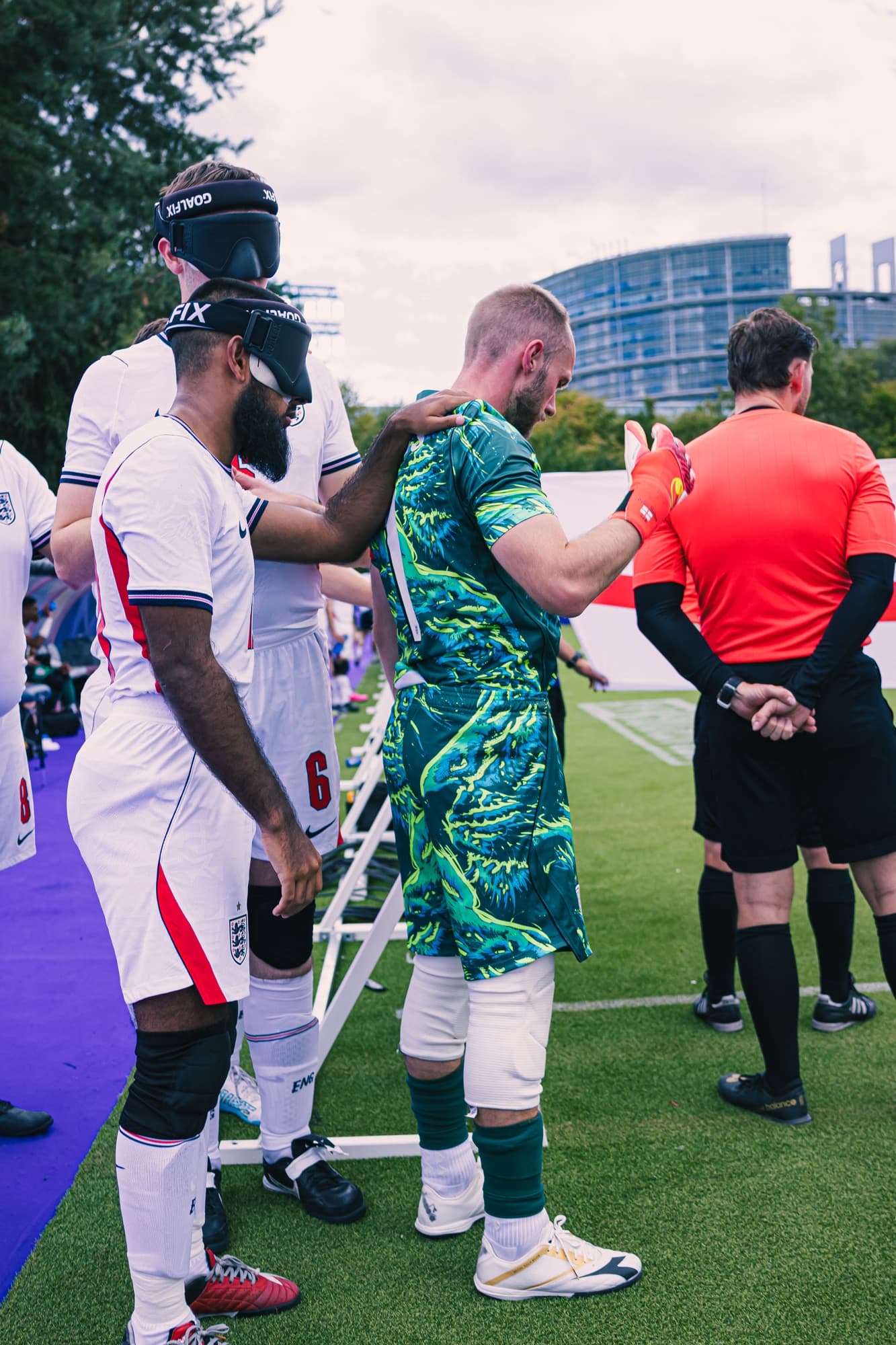 Un joueur et son guide avant un match de l’Euro de cécifoot, avec l’arbitre au bord du terrain