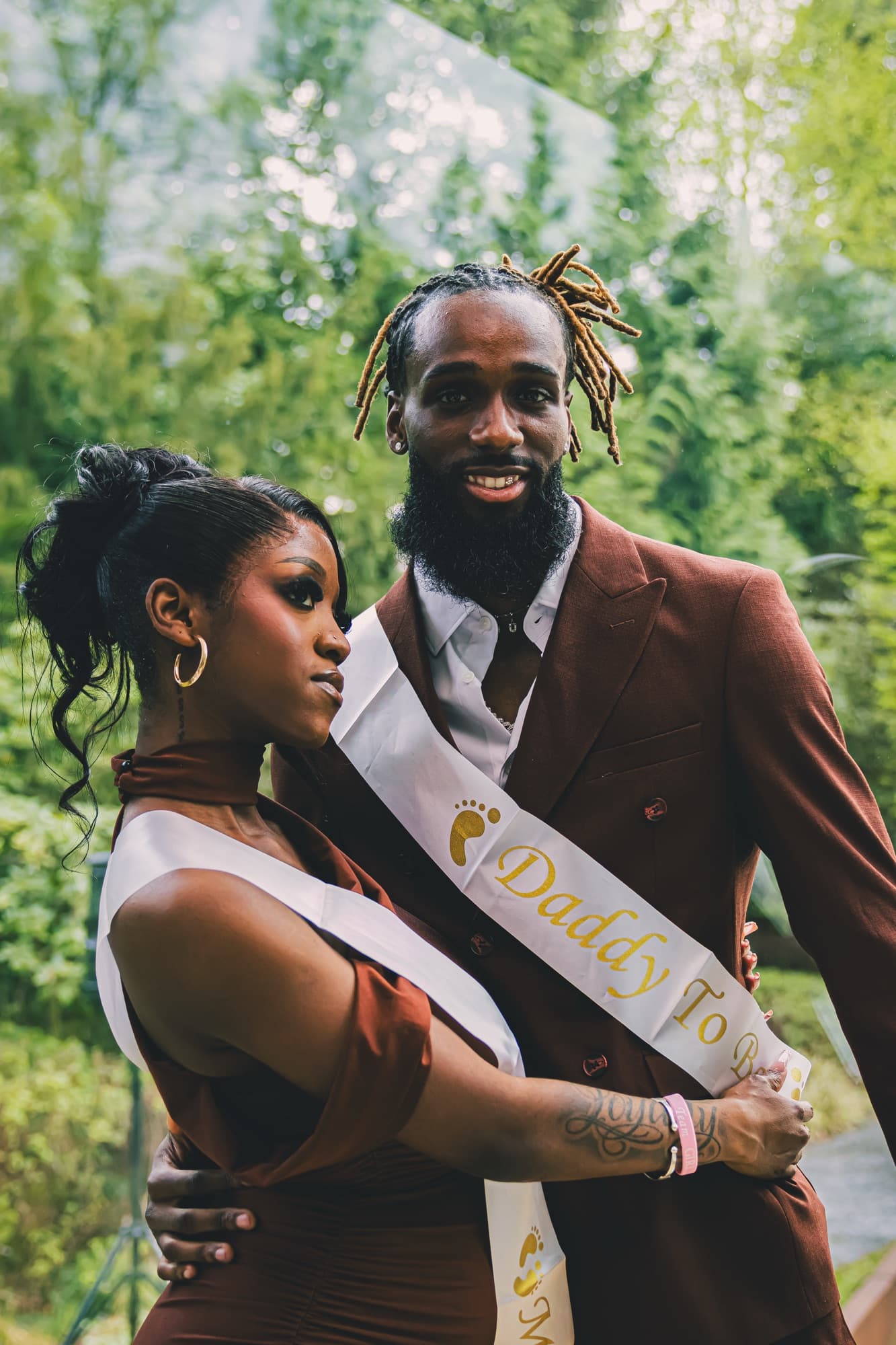 Le couple de futurs parents enlacé, souriant, dans le jardin, pendant le gender reveal
