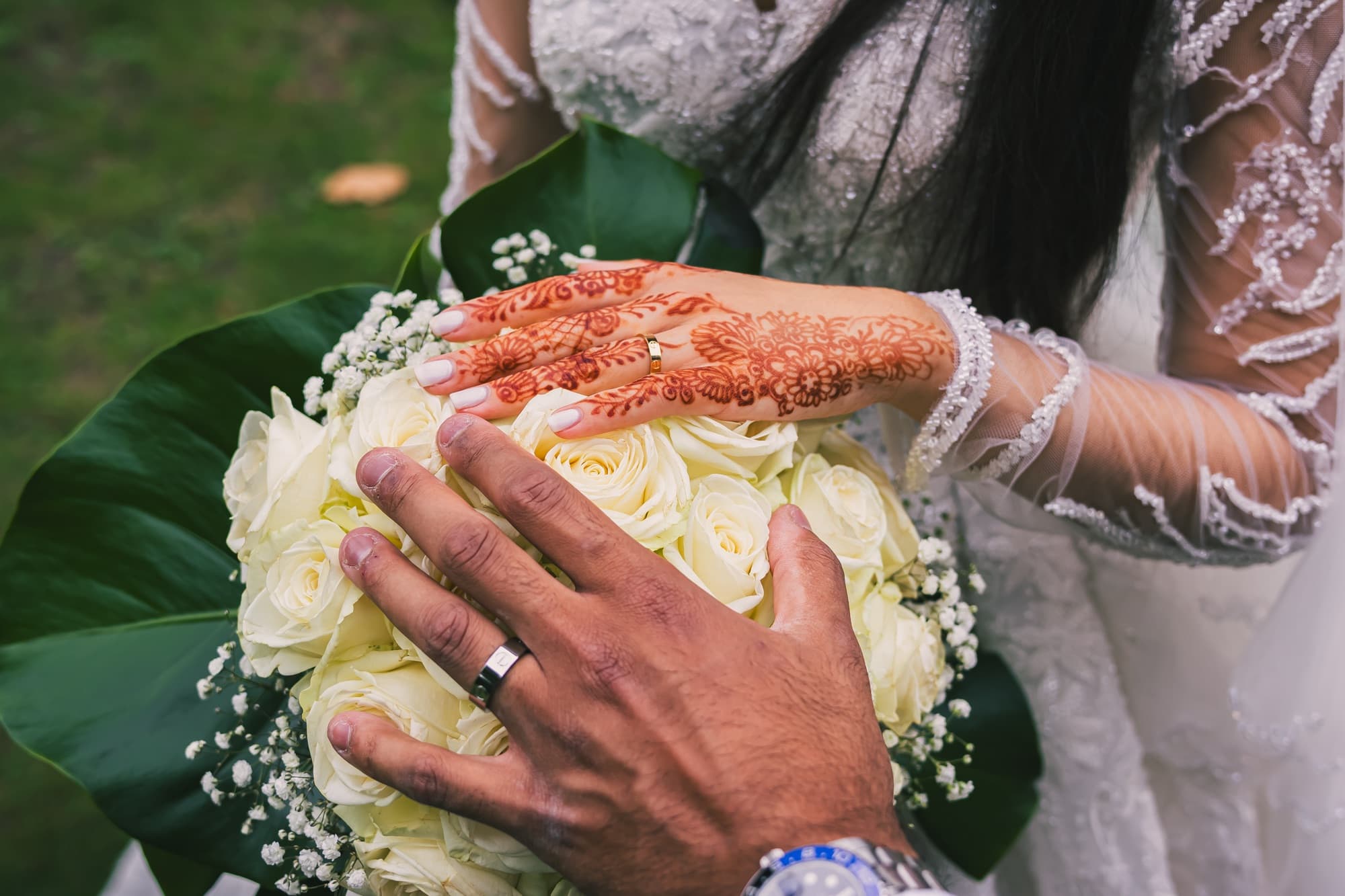Le bouquet de roses blanches et de gypsophile tenu entre les mains des mariés, sur la robe en dentelle