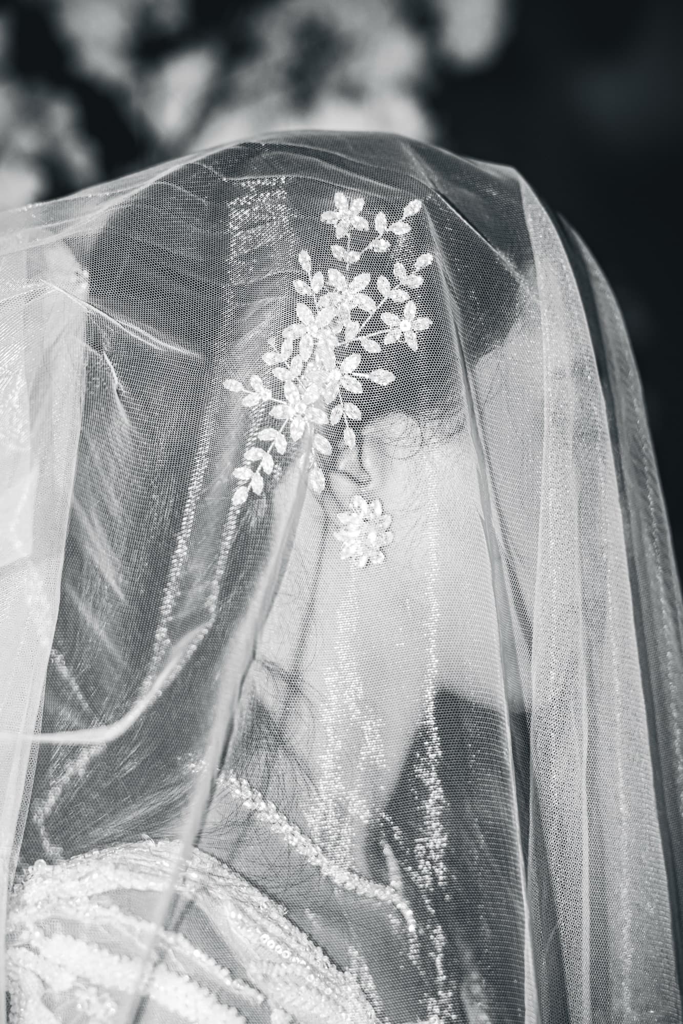 Le voile de la mariée et son bijou de cheveux brodé de fleurs, en noir et blanc