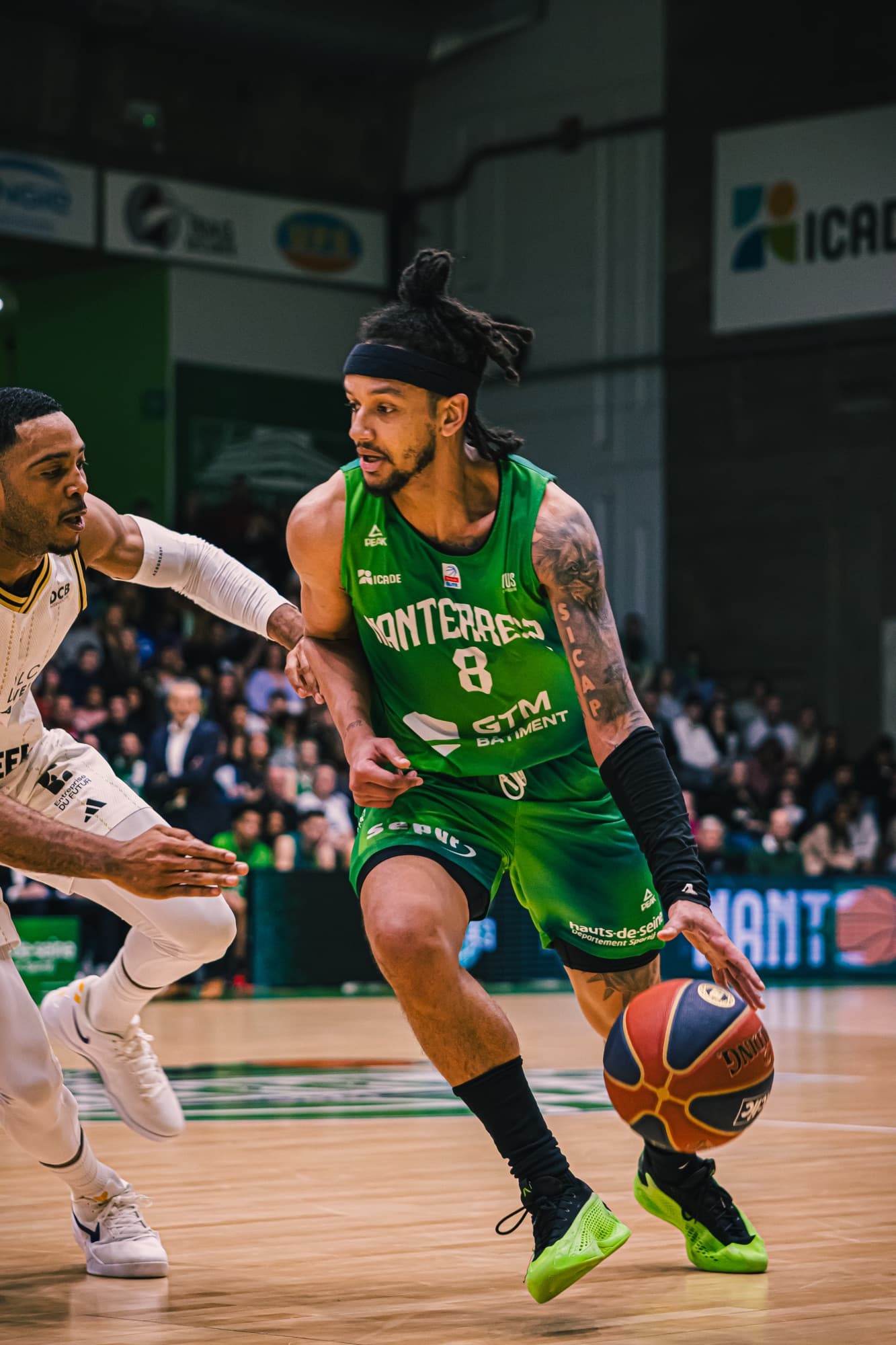 Un joueur de Nanterre 92 en vert dribble face à un défenseur d’ASVEL