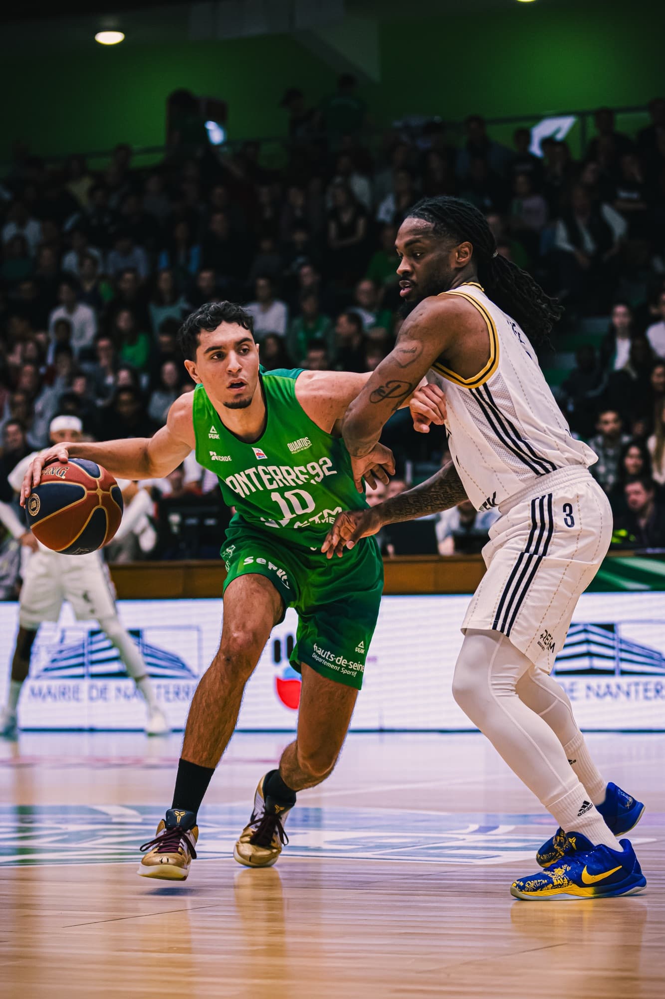 Un joueur de Nanterre 92 protège le ballon face à un défenseur d’ASVEL en blanc