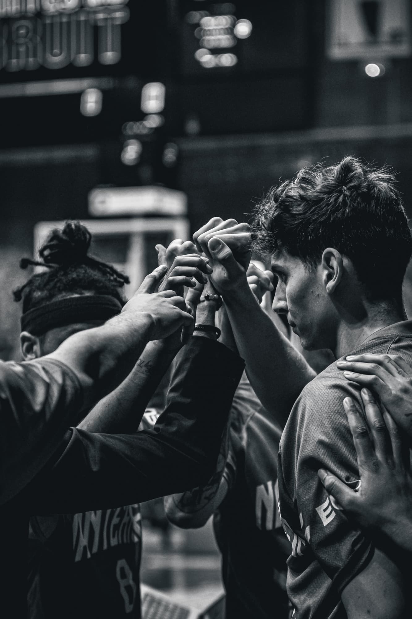Les mains des joueurs de Nanterre 92 réunies au centre du groupe, en noir et blanc