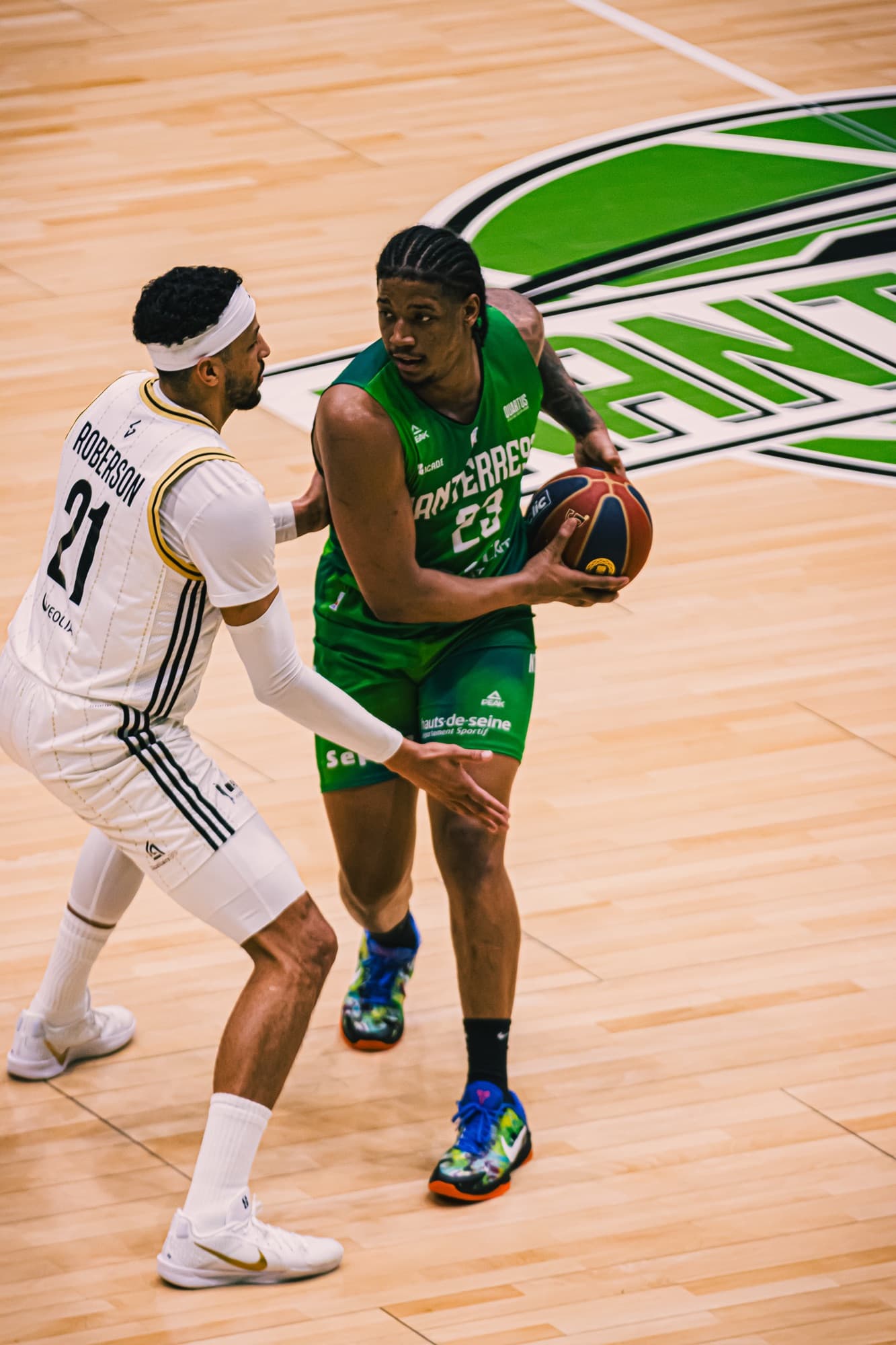 Un joueur de Nanterre 92 en vert garde le ballon face à un défenseur d’ASVEL