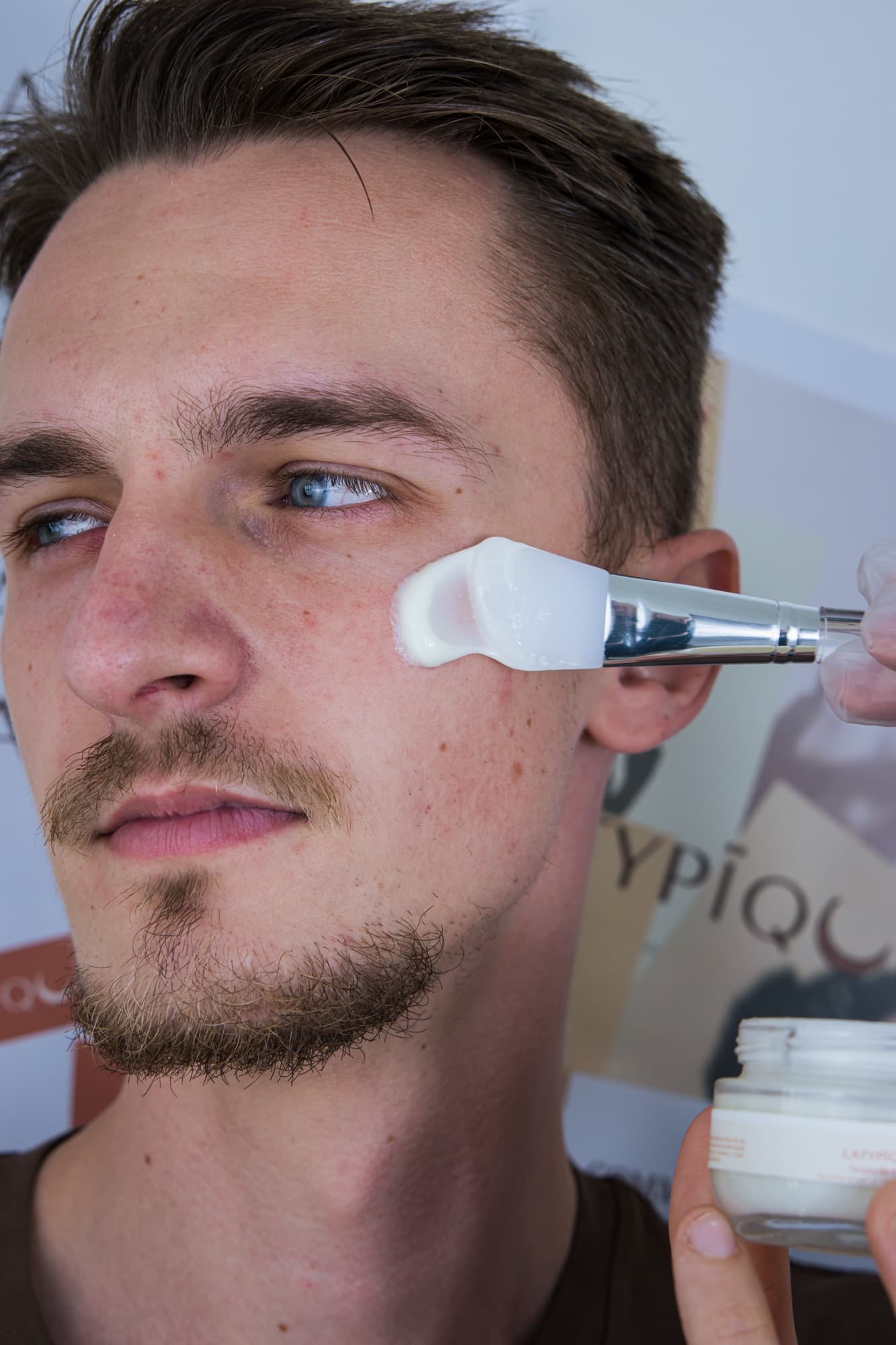 Un homme se fait appliquer la crème de nuit sur la joue avec un pinceau en silicone
