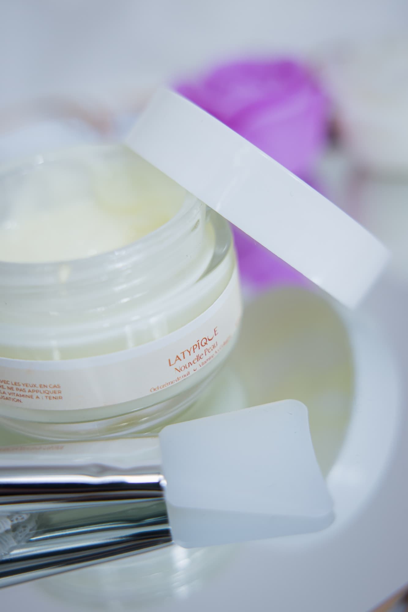 Pot ouvert de gel crème de nuit et pinceau en silicone sur un plateau miroir doré
