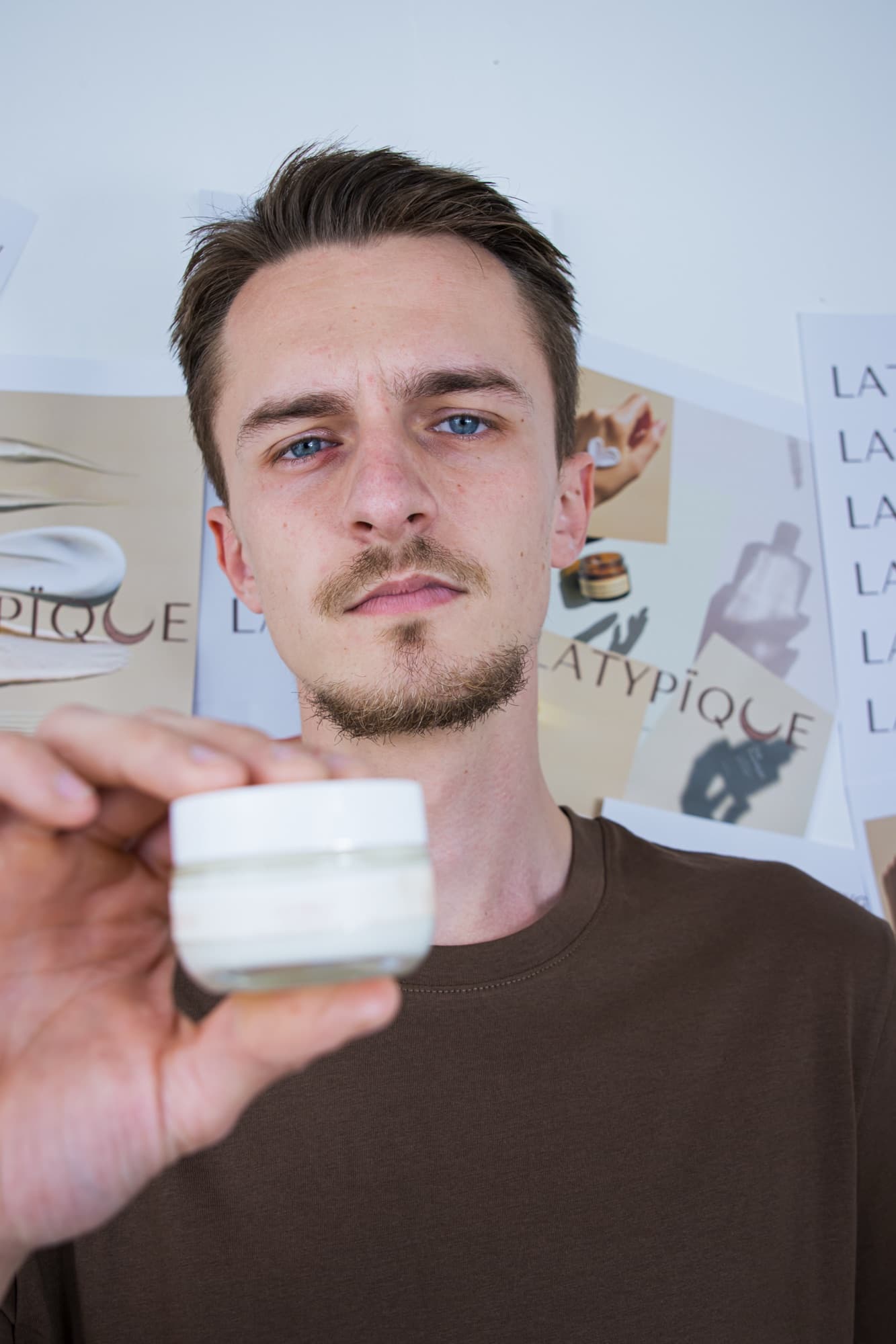 Portrait d’un homme tenant le pot de gel crème de nuit Nouvelle Peau à côté de son visage