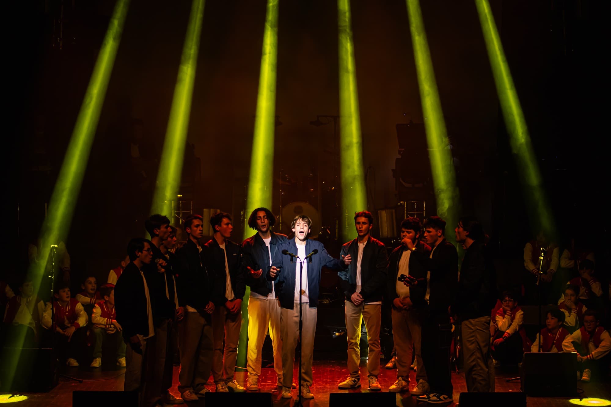 Les choristes en haut de scène sous des faisceaux lumineux jaunes