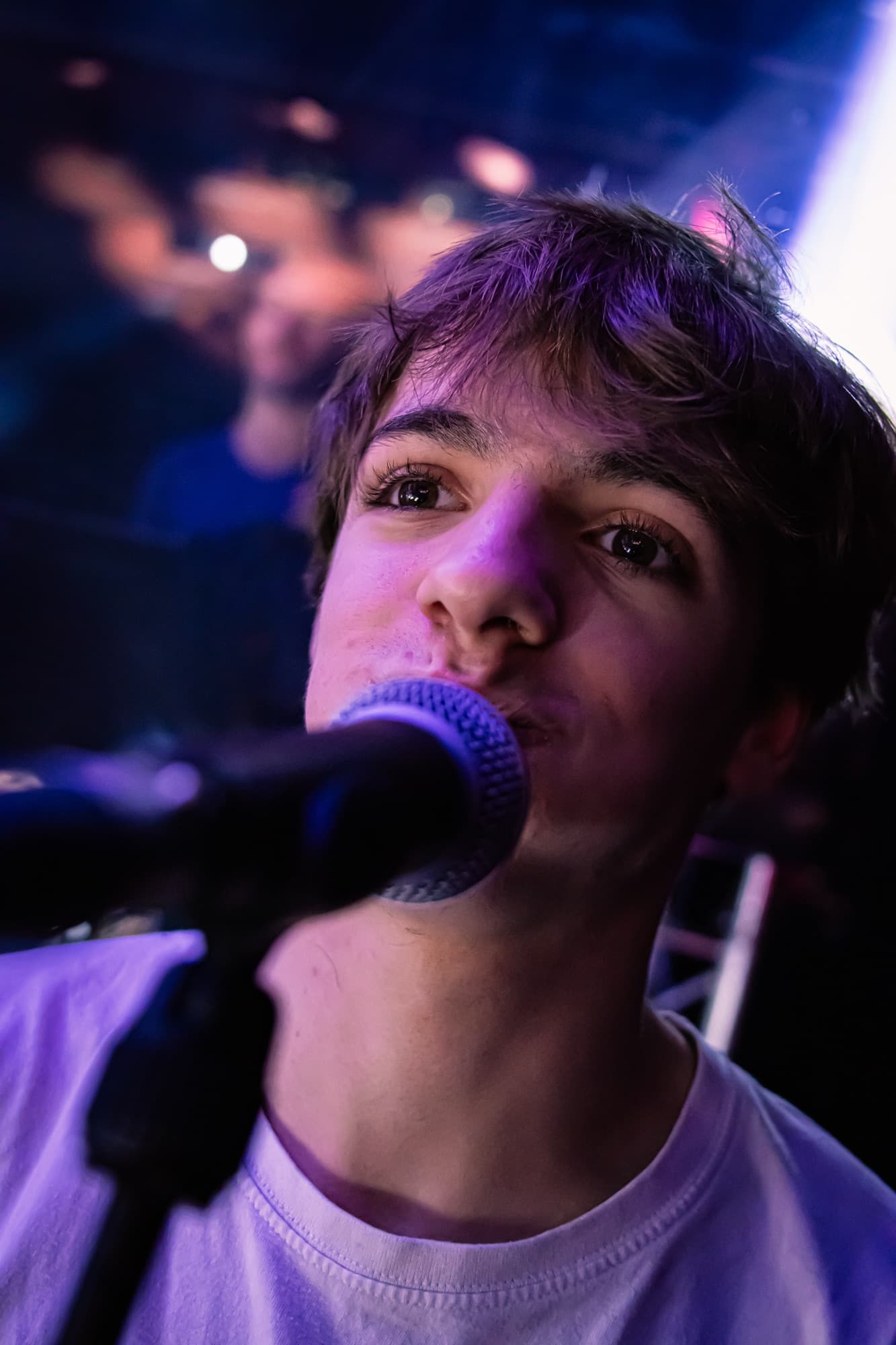 Gros plan d’un jeune chanteur face au micro, la tête levée