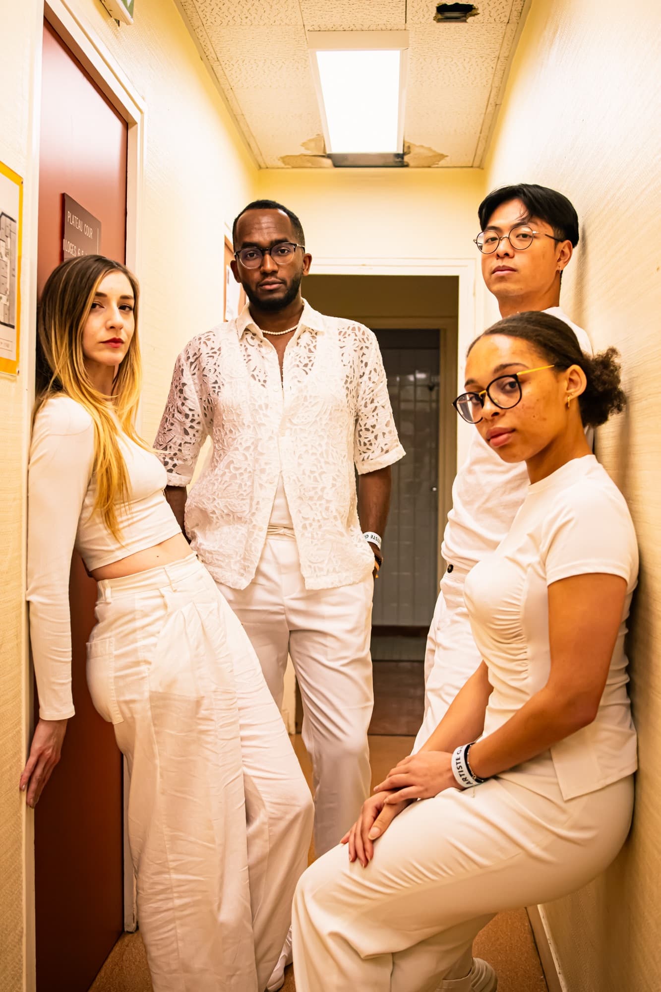 Portrait de quatre invités en blanc dans un couloir, dans les coulisses du gala