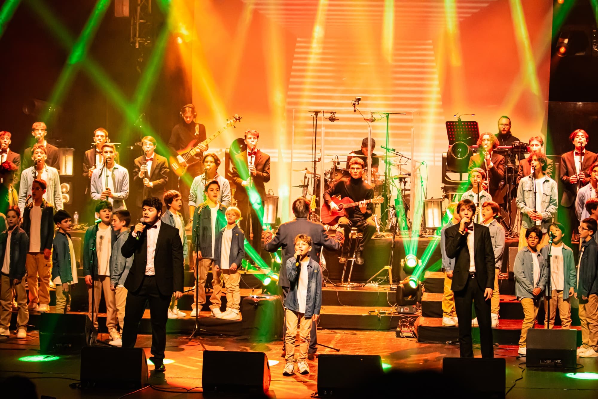 Le chœur et l’orchestre sur scène sous des lumières orange et vertes