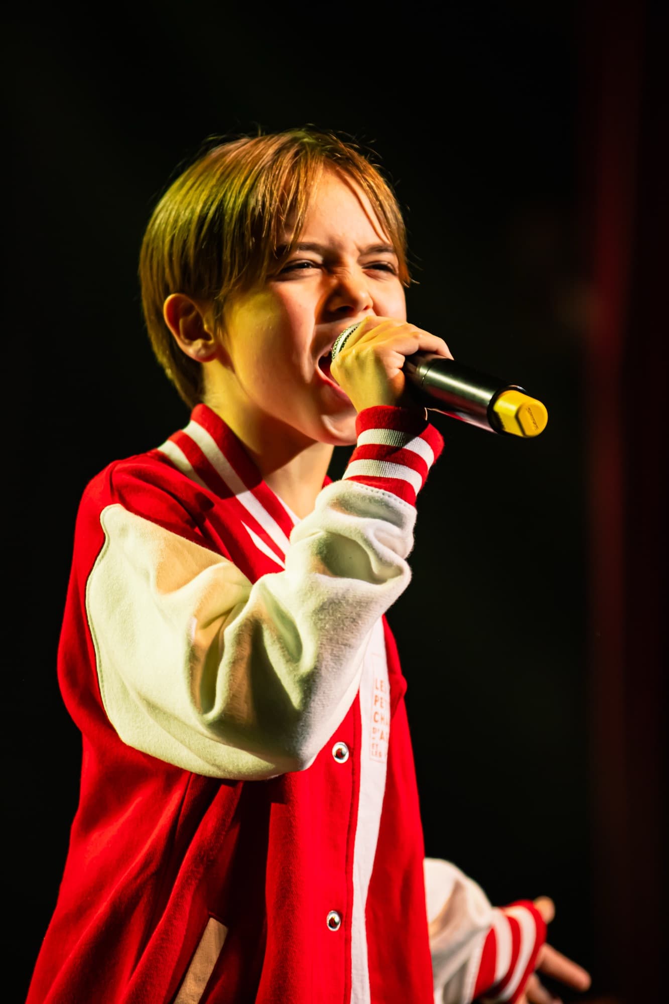 Un jeune soliste en veste rouge et blanche chante dans le micro