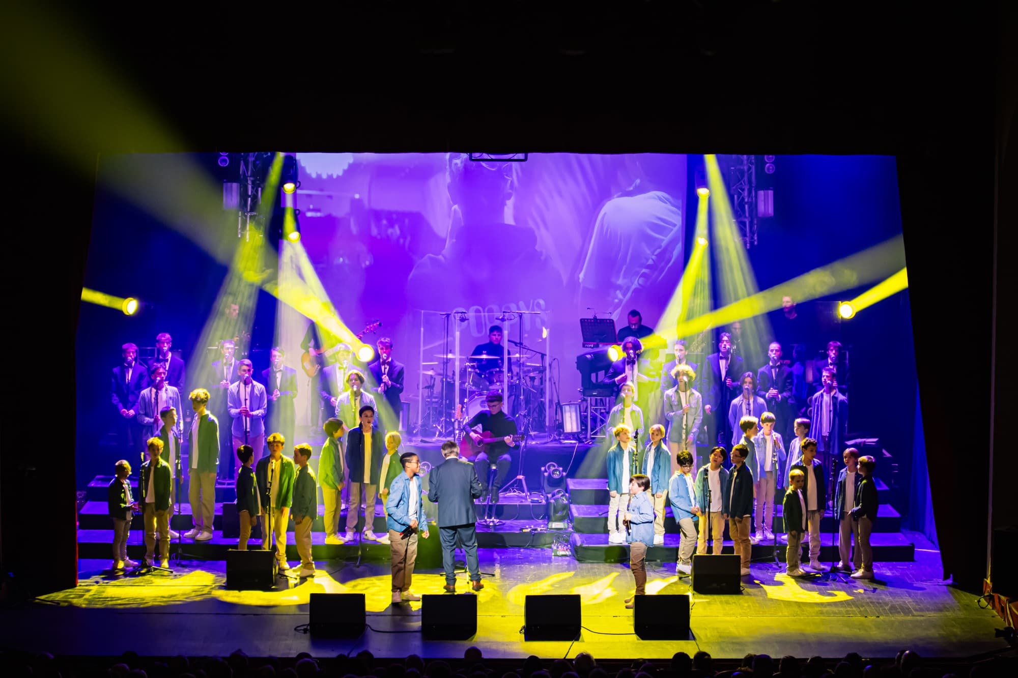 Vue large de la scène du gala 2024 des Petits Chanteurs d’Asnières, éclairée en jaune et en violet
