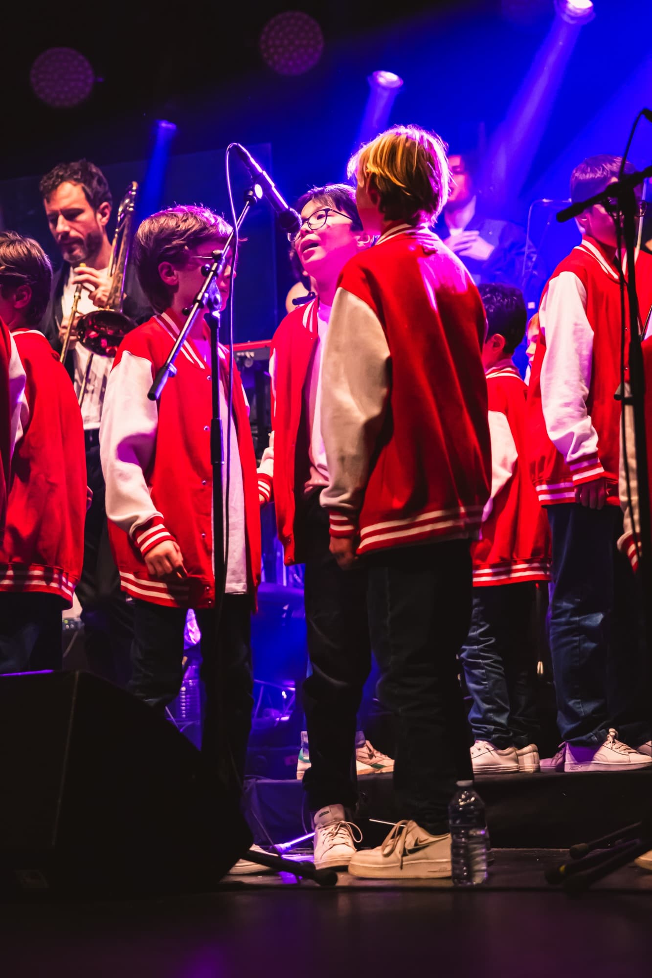 Les choristes en vestes rouges et blanches, de dos et de profil
