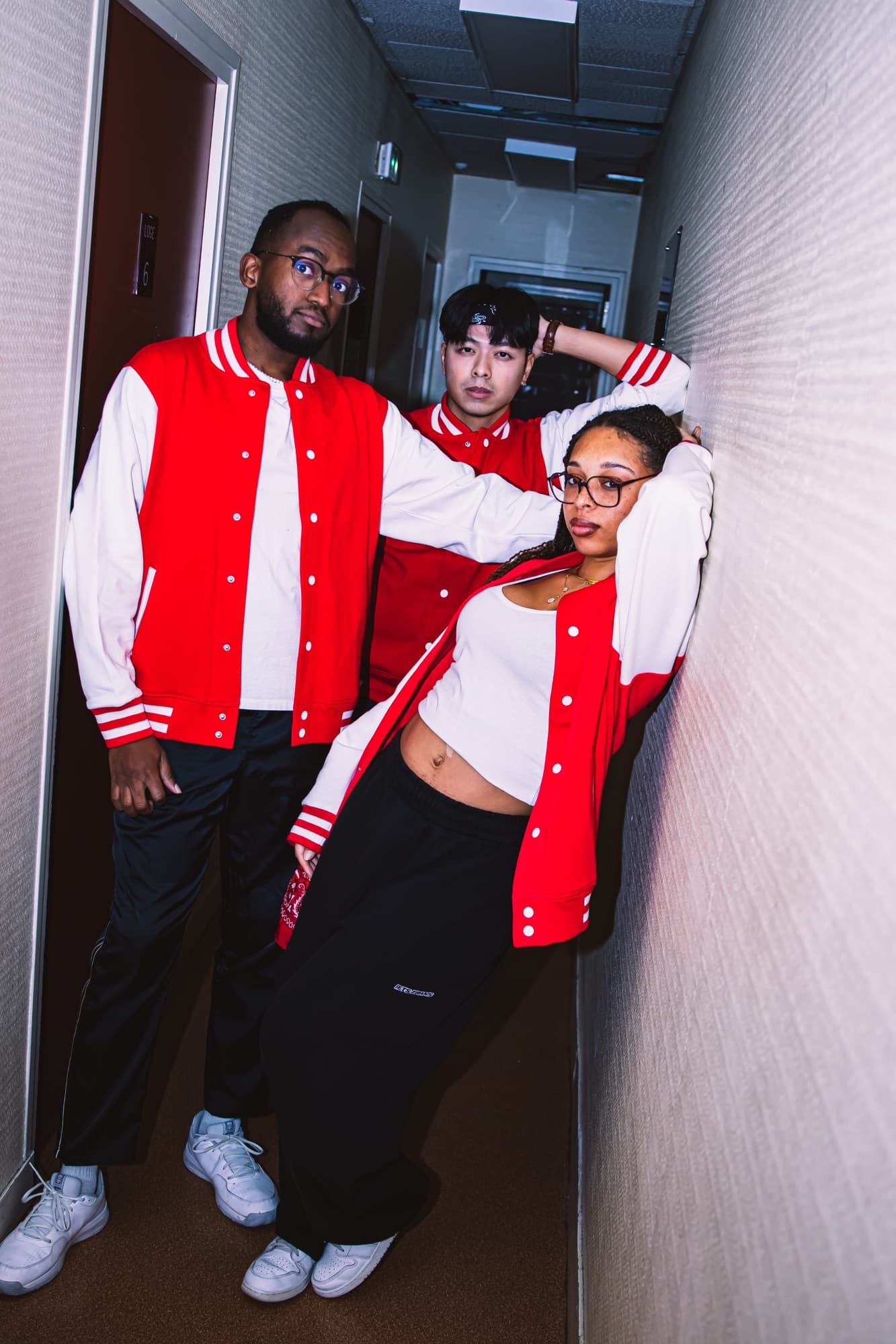 Trois danseurs en vestes rouges et blanches dans un couloir, avant le gala