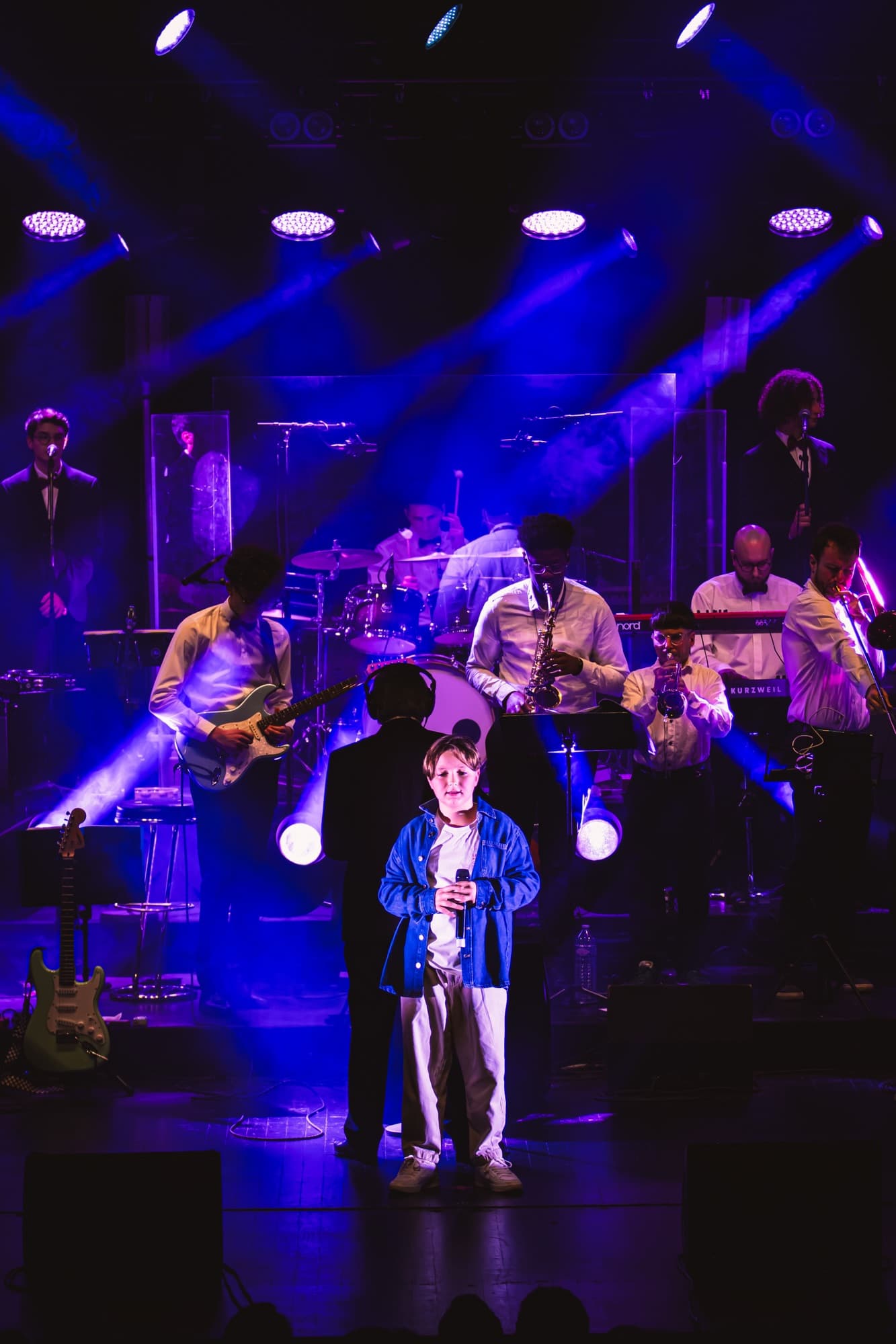 Un jeune soliste devant l’orchestre, sous des projecteurs bleus