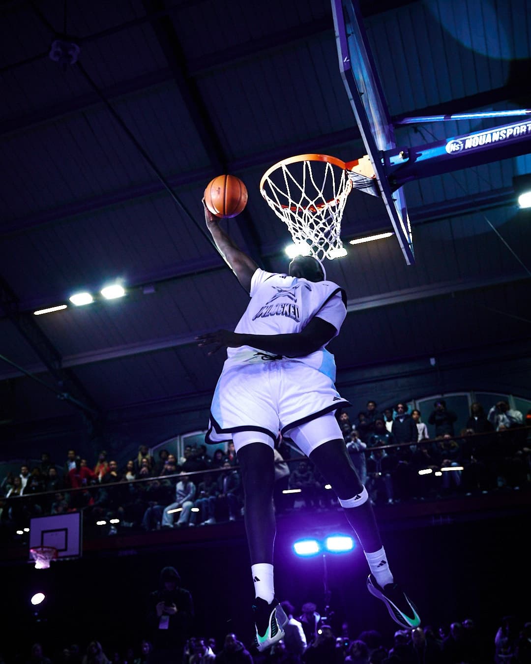 Dunk spectaculaire sous les projecteurs, la salle derrière lui