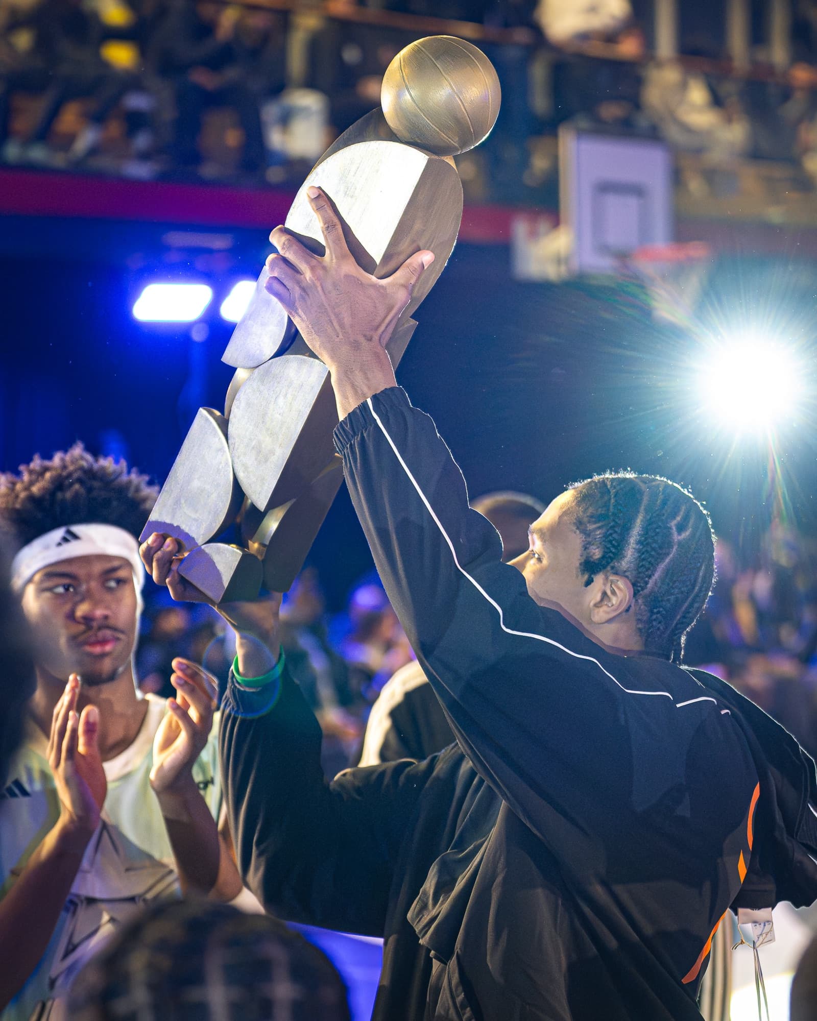 Remise du trophée : le trophée est levé sous les projecteurs, les joueurs applaudissent