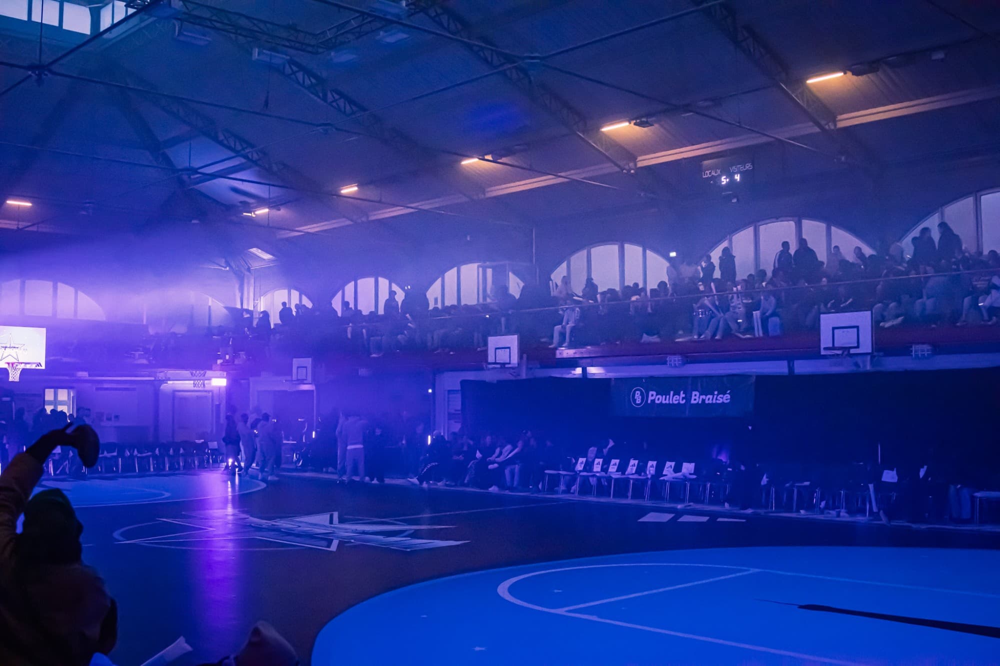 La salle dans la fumée et les lumières violettes, tribunes remplies
