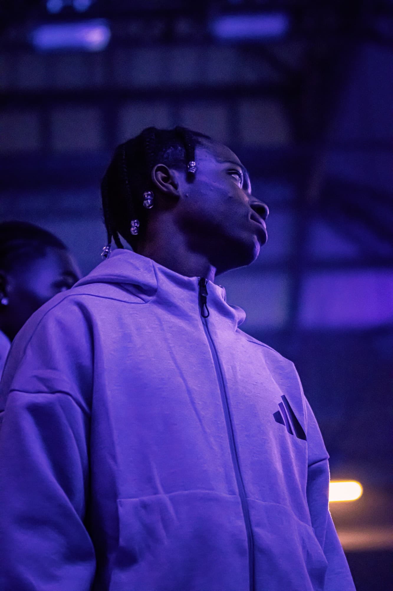 Portrait d’un jeune homme en sweat adidas, sous une lumière violette